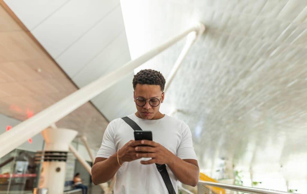 Mann am Flughafen, hält Handy in der Hand, NO-GOs am Smartphone